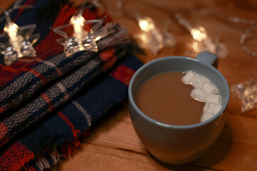 a mug of hot chocolate with marshmallows on the table and lights