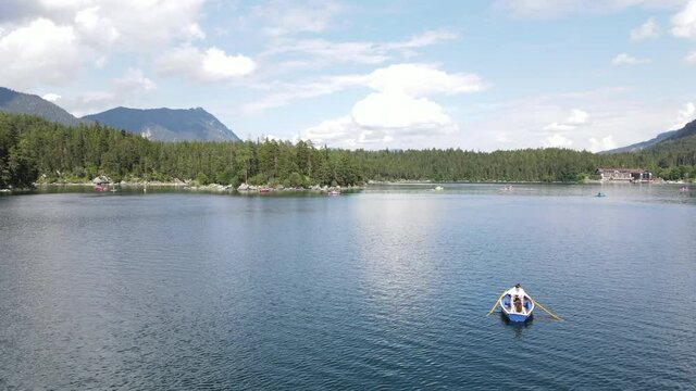 Couple on a rowboat shipping over a lake, Eibsee, aerial drone shot, nature, lovers, vertical jib, movement downwards