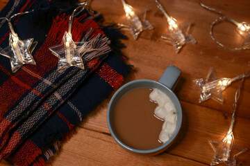 a mug of hot chocolate with marshmallows on the table and lights