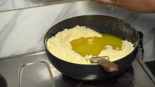 Puring pure cow ghee in the besan flour to prepare ladoo.