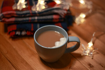 a mug of hot chocolate with marshmallows on the table and lights