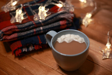 a mug of hot chocolate with marshmallows on the table and lights