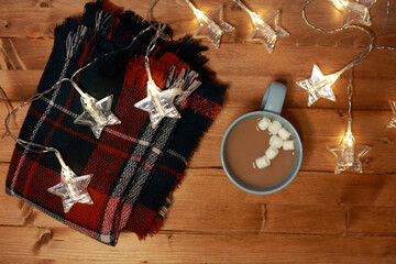 a mug of hot chocolate with marshmallows on the table and lights