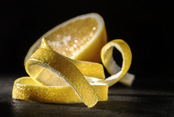 Lemon peel with lemon on a dark background, close-up.