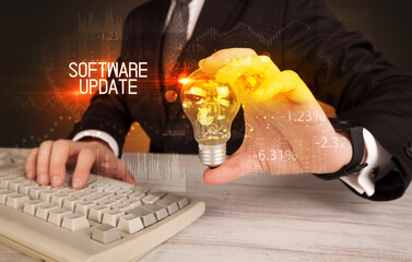 Businessman holding lightbulb with SOFTWARE UPDATE inscription, Business technology concept