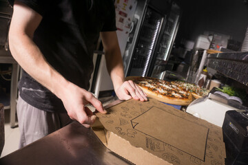 Man packing pizza in a box. Pizza in a cardboard box.