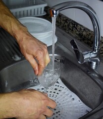 Manos de hombre fregando los platos y vajilla en la cocina