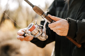 Close-up of a woman holding a fishing rod with a reel, sport fishing.