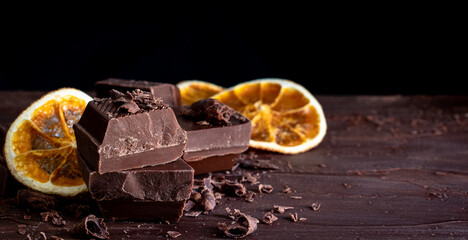 Organic food snack tasty sweet dessert milk dark chocolate bar macro closeup broken slide piece and fruit orange raspberry hazelnut nuts on cocoa cacao powder wooden table for new year Christmas gift