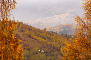Fototapeta premium Villages in Romania, amazing view of the authentic places from Rucar-Bran area at the bottom of Bucegi and Piatra Craiului Mountains during an autumn foggy cloudy day with great colors