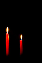 Two red burning candles, dark background