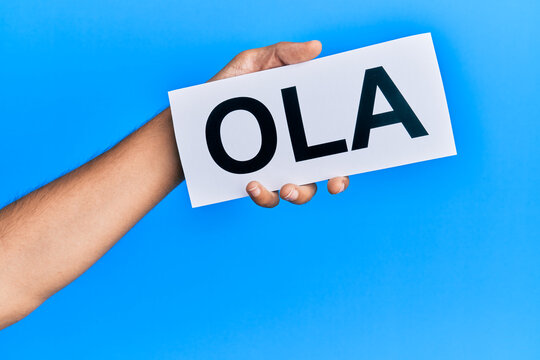 Hand of hispanic man holding ola word paper over isolated blue background.