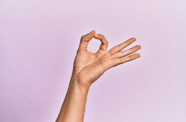 Arm and hand of caucasian young man over pink isolated background gesturing approval expression doing okay symbol with fingers
