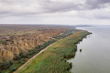 Obraz premium Aerial view at huge lake with beautiful sand dunes and green shore and early evening sky