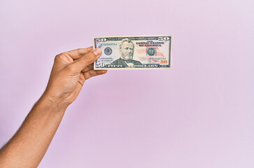 Hispanic hand holding 50 usa dollars banknote over isolated pink background.