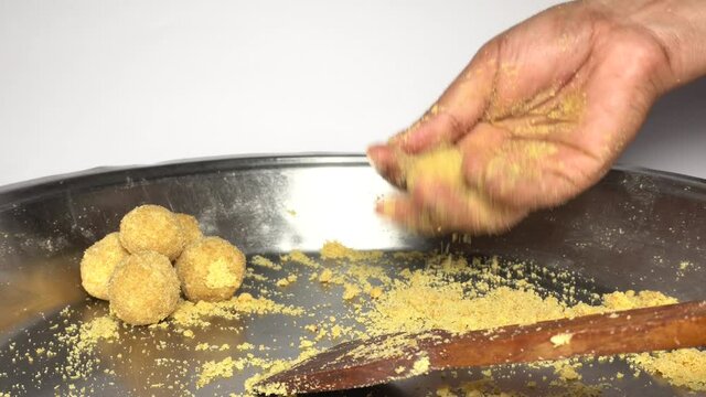 A female hand rolling "Laddu" in hand during diwali festival. Sweet snack consumed in India while deepavali.