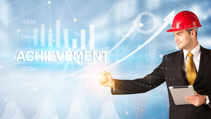 Young businessman with helmet drawing ACHIEVEMENT inscription, modern business technology concept