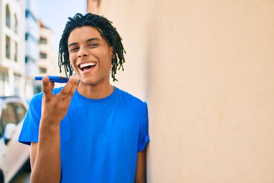 Young african american man sending audio message using smartphone at street of city.