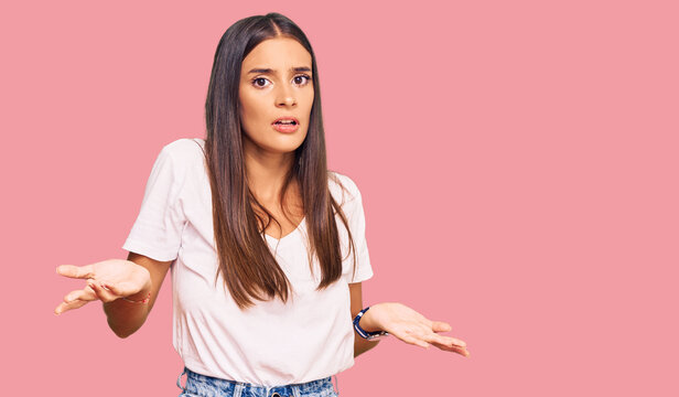 Young hispanic woman wearing casual white tshirt clueless and confused with open arms, no idea concept.