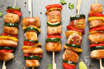 Delicious chicken shish kebabs with vegetables and herbs on grey table, flat lay