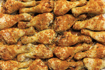 Herbs and spices covering chicken drumsticks.