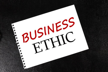 BUSINESS ETHIC, text on white paper torn from notepad on black background