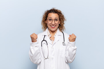 hispanic middle age woman feeling shocked, excited and happy, laughing and celebrating success,...