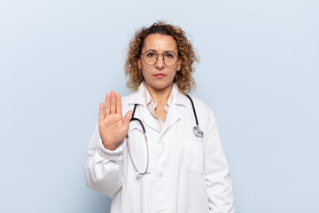 hispanic middle age woman looking serious, stern, displeased and angry showing open palm making...