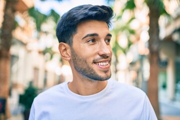 Young latin man smiling happy walking at the city.