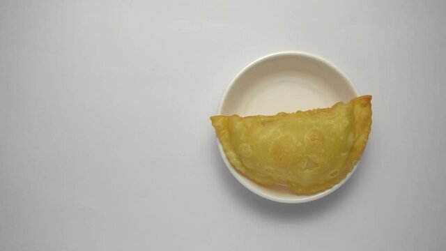 A female hand serving "Karanji" a sweet maharashtriyan deep fried food in the plate. Snack consumed during diwali festival.