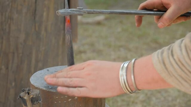Slow motion: professional blacksmith working with spearhead on anvil at outdoor workshop - close up view. Handmade, reenactment, craftsmanship, medival, revival concept