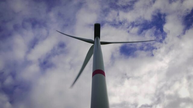 Looking up to a wind turbine infront of blue sky