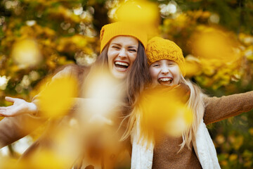 happy modern mother and daughter throws up autumn leaves