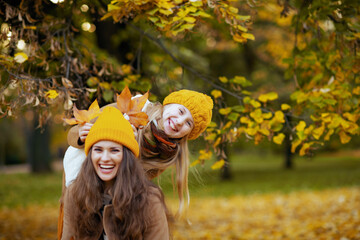 mother and child having fun time outside on city park in autumn