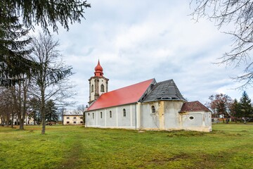 Nova Ves / Czech Republic - November 15 2020: View of the roman catholic church of the Most Holy Trinity built in the 18th century standing in the park with trees and green grass.