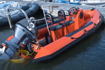 An orange RIB - Rigid Inflatable Boat tied up to a pontoon in a marina