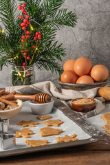 Making christmas gingerbread cookies. Raw dough in shape of gingerbread man, christmas tree, star, snowflakes on paper on tray on rustic table with rolling pin. Preparing for baking
