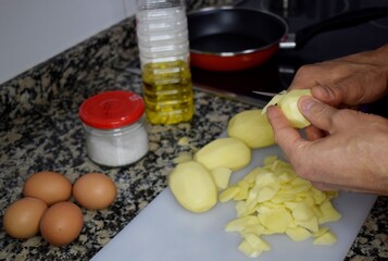 hombre cocinando, pelando patatas para hacer una tortilla española