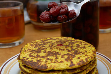 Fresh hot pancakes with cherry jam on plate