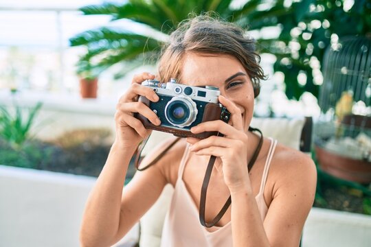 Young beautiful caucasian woman smiling happy at home taking pictures using vintage camera