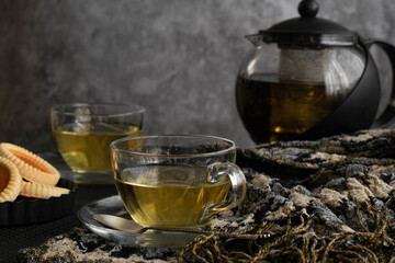 Relaxing tea time concept. Dark mood view of herbal tea and cookies