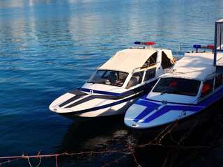Two patrol boats are parked in the water behind barbed wire