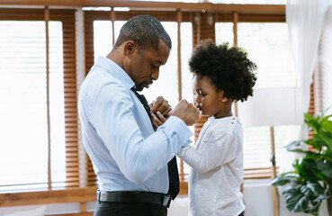 Happy African American Father and son spend time together. Little boy helping his father tie...