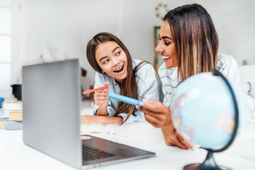A teen child spends time with his mother at the computer. Studying at home
