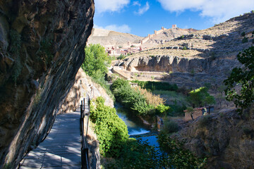 Hiking river route along the Guadalaviar river with the town and walls of Albarracin in the background, Teruel, Spain
