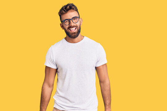 Young hispanic man wearing casual clothes and glasses winking looking at the camera with sexy expression, cheerful and happy face.