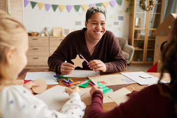 Portrait of smiling female teacher looking at children during art and craft class in school, copy...