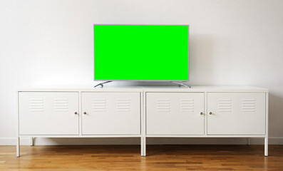 Widescreen modern green screen TV for text and video on chrome stand against a white wall in a...