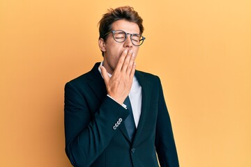 Handsome caucasian man wearing business suit and tie bored yawning tired covering mouth with hand. restless and sleepiness.