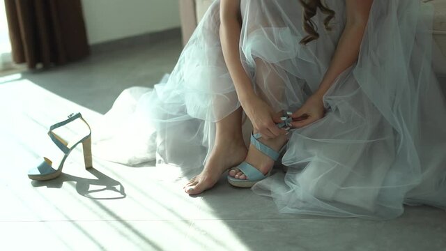the bride buttons up her sandal while preparing for the wedding ceremony